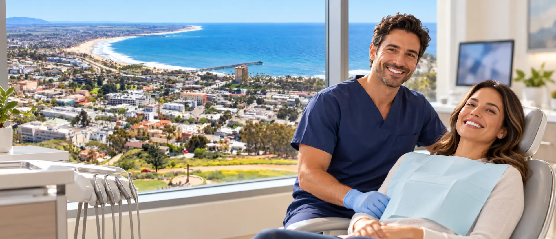 Dentist smiling beside a relaxed patient in a bright clinic with a window view of Ventura and the ocean