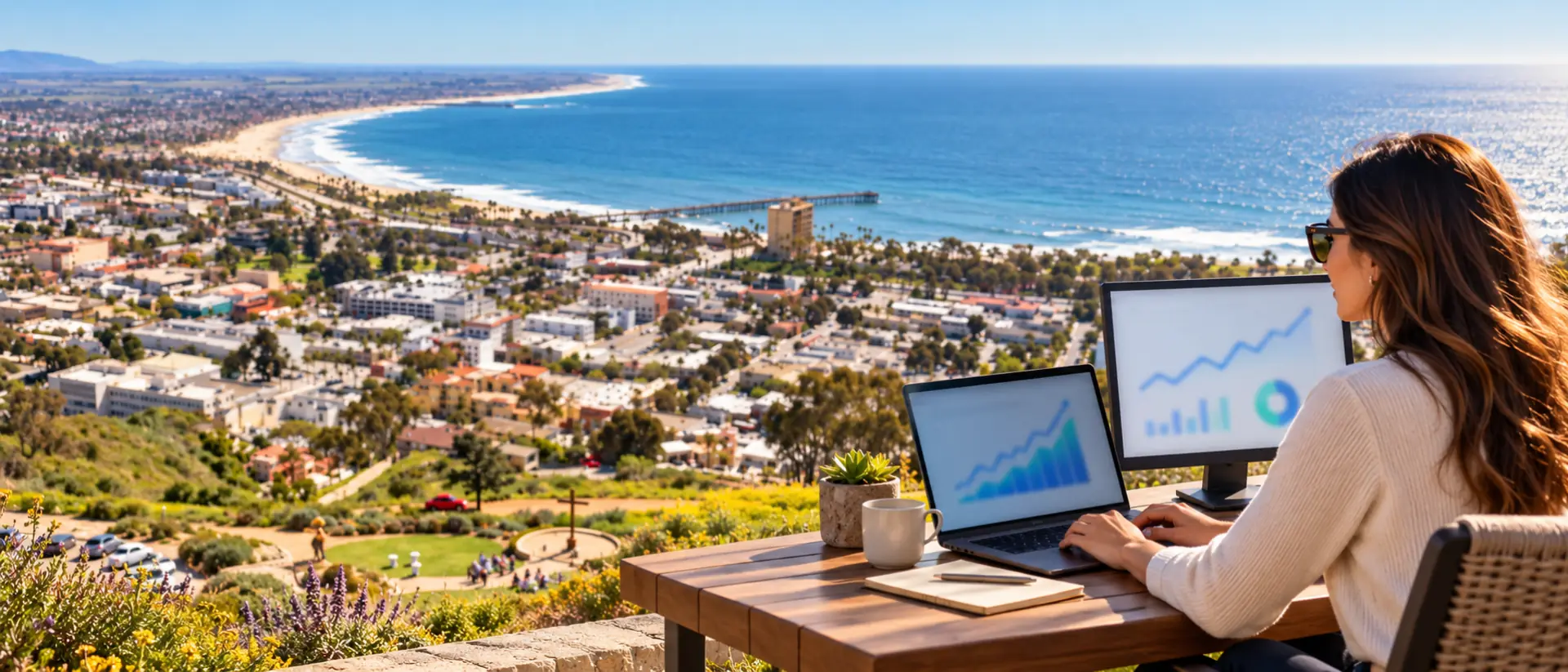 Search marketing analyst working on a laptop with analytics charts on a terrace above Ventura and the coast